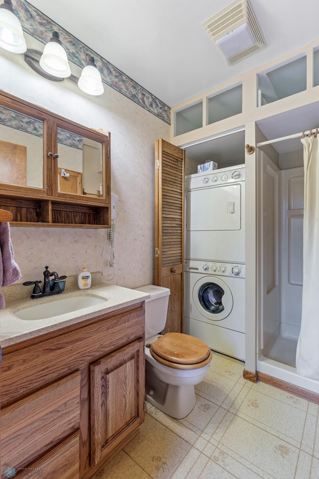 bathroom featuring tile patterned flooring, walk in shower, toilet, stacked washing maching and dryer, and vanity