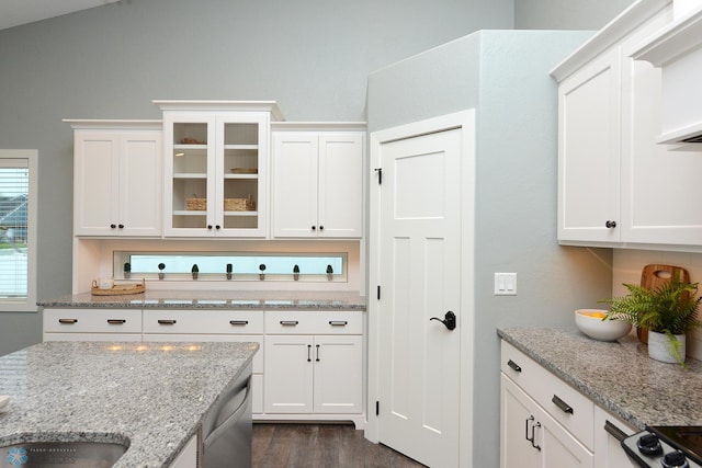 kitchen with white cabinets, vaulted ceiling, stainless steel dishwasher, light stone countertops, and dark hardwood / wood-style flooring