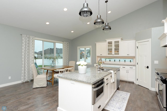 kitchen featuring appliances with stainless steel finishes, dark hardwood / wood-style flooring, lofted ceiling, and a center island with sink