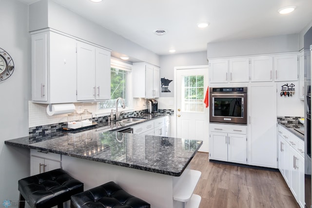 kitchen featuring white cabinetry, light wood-type flooring, and stainless steel oven