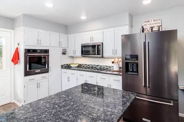 kitchen featuring dark stone counters, white cabinetry, light hardwood / wood-style floors, and appliances with stainless steel finishes