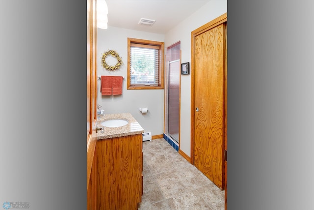 bathroom with tile patterned floors, a baseboard heating unit, a shower with door, and vanity