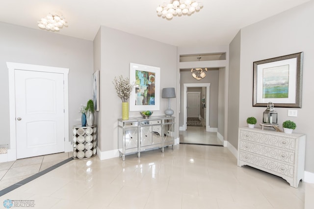 corridor with a notable chandelier and tile patterned floors