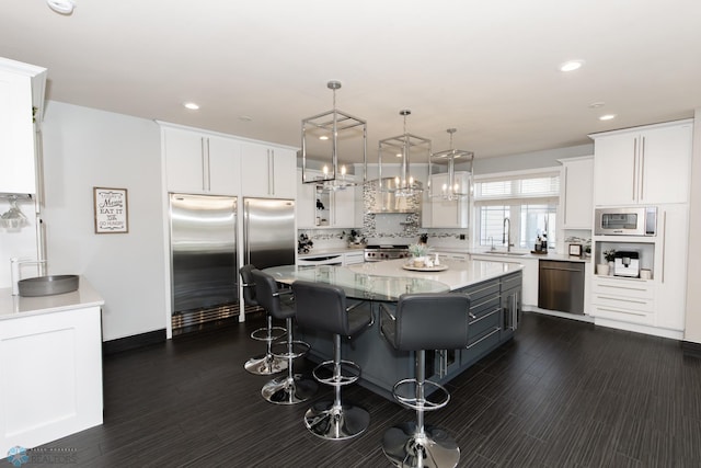 kitchen featuring white cabinetry, dark hardwood / wood-style flooring, a kitchen island, built in appliances, and decorative backsplash