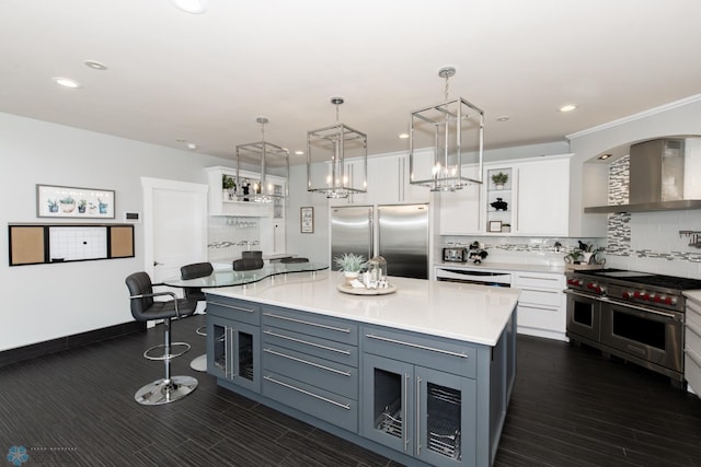 kitchen with white cabinetry, tasteful backsplash, wall chimney exhaust hood, a kitchen island, and high quality appliances