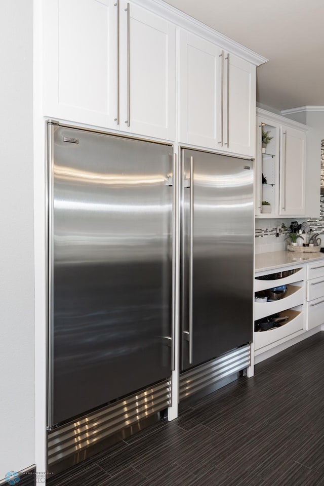 kitchen with white cabinetry, backsplash, light stone counters, and built in fridge