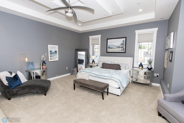 carpeted bedroom with ceiling fan and a tray ceiling