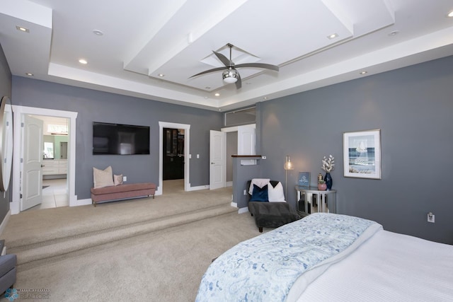 bedroom with a tray ceiling, light colored carpet, a walk in closet, and ceiling fan