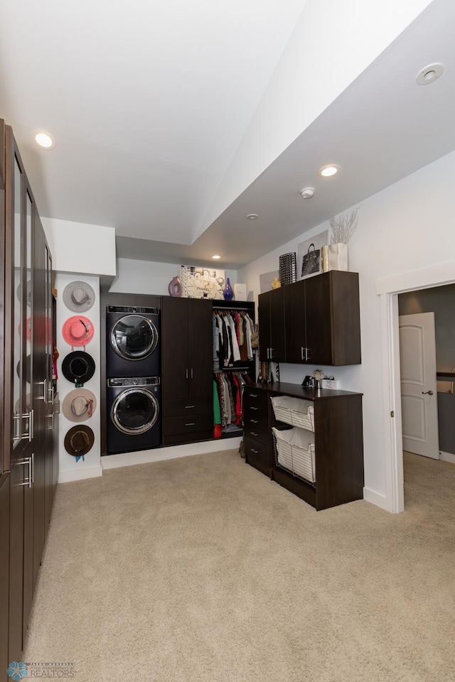 interior space with stacked washer / dryer, vaulted ceiling, light colored carpet, and dark brown cabinets