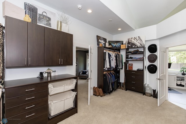 walk in closet featuring lofted ceiling and light colored carpet