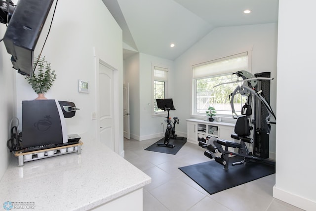 workout room with light tile patterned floors and vaulted ceiling