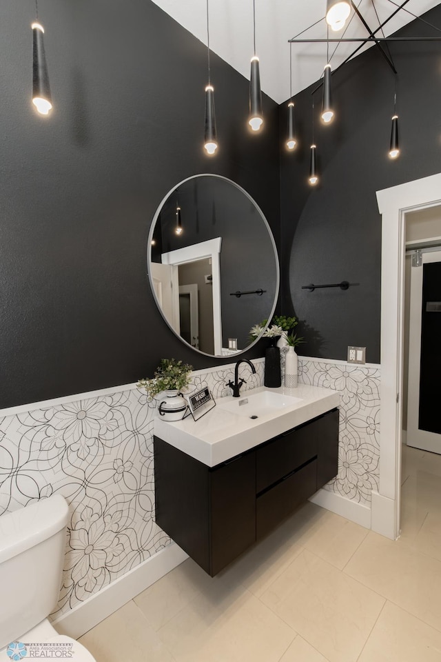 bathroom featuring tile patterned flooring, toilet, vanity, and a high ceiling