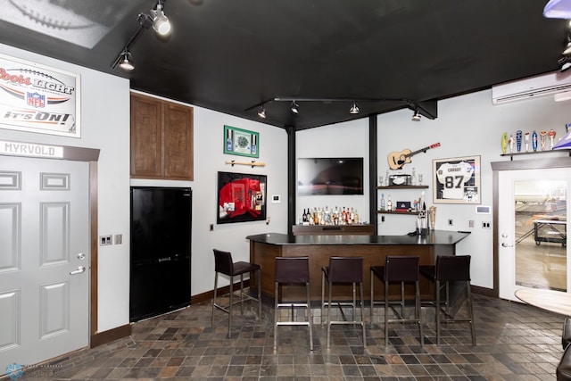 bar featuring an AC wall unit, rail lighting, and dark tile patterned flooring