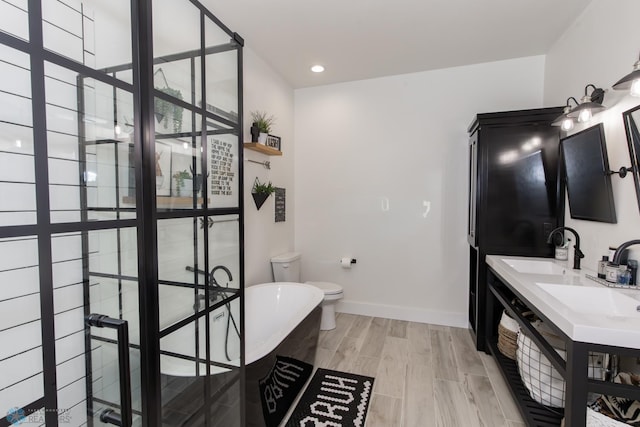 bathroom with double vanity, a tub to relax in, wood-type flooring, and toilet