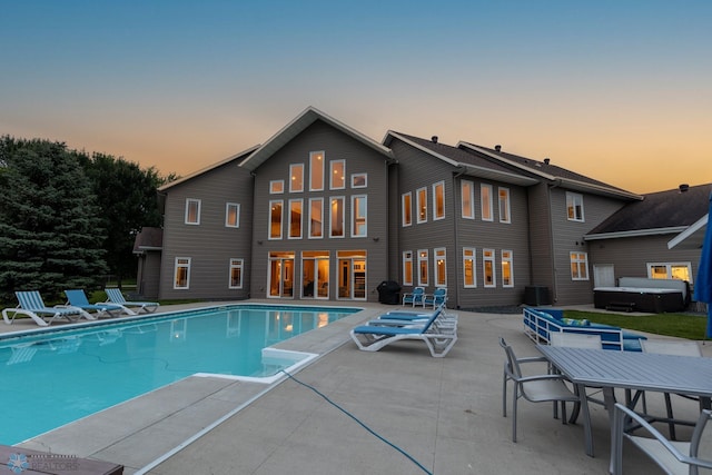 pool at dusk featuring central air condition unit and a patio area