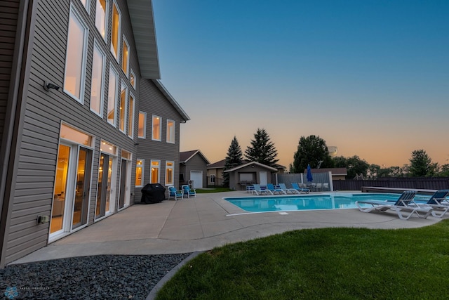 pool at dusk with a yard and a patio area