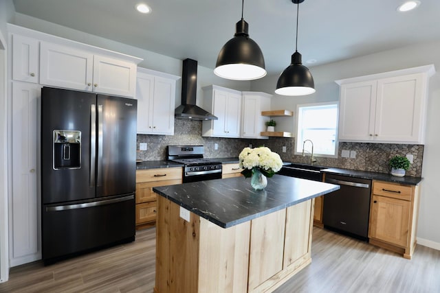 kitchen featuring wall chimney exhaust hood, black refrigerator with ice dispenser, stainless steel stove, dishwasher, and a kitchen island