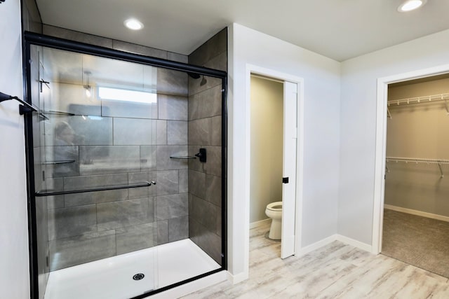 bathroom featuring a shower with shower door, toilet, and hardwood / wood-style floors