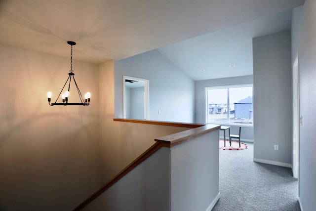 corridor featuring a notable chandelier, carpet floors, and vaulted ceiling