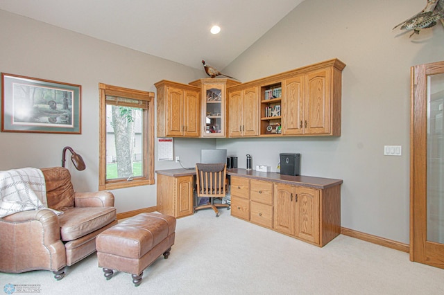 carpeted home office with vaulted ceiling and built in desk