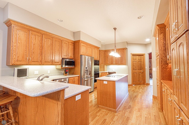 kitchen featuring decorative light fixtures, stainless steel appliances, a center island, light hardwood / wood-style floors, and kitchen peninsula