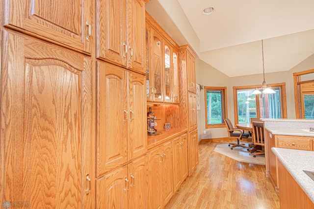 kitchen with pendant lighting, vaulted ceiling, and light hardwood / wood-style flooring