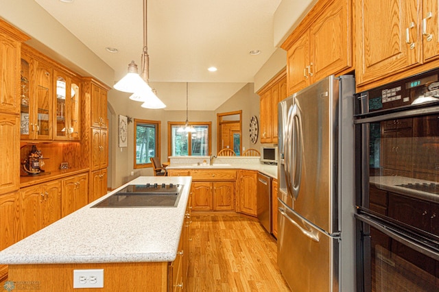 kitchen with hanging light fixtures, black appliances, light wood-type flooring, and a kitchen island