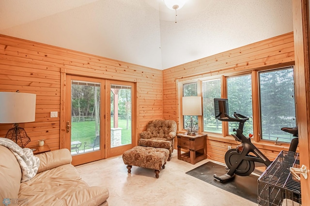 living room featuring high vaulted ceiling, a textured ceiling, and wooden walls