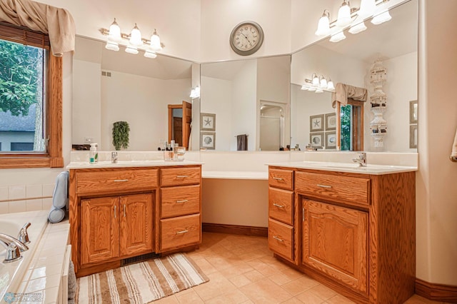 bathroom with double vanity, tiled tub, and tile patterned flooring