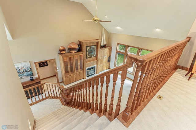 stairs with high vaulted ceiling, ceiling fan, and light colored carpet