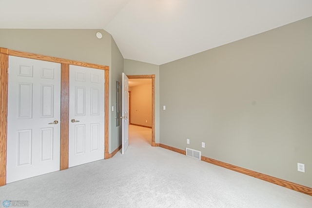 unfurnished bedroom with carpet flooring, lofted ceiling, and a closet