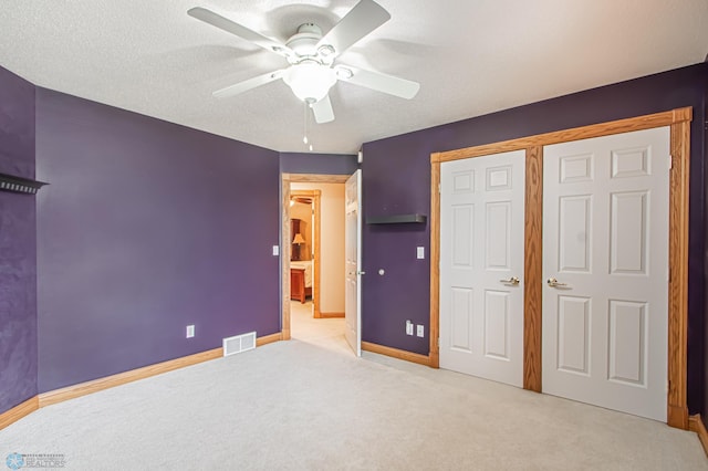 unfurnished bedroom with a textured ceiling, carpet, ceiling fan, and a closet