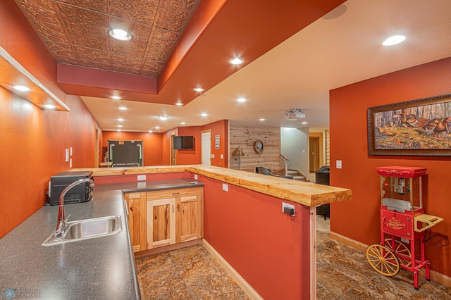 kitchen featuring butcher block countertops, sink, kitchen peninsula, and dark tile patterned flooring