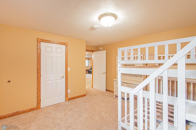 interior space with a textured ceiling and light colored carpet