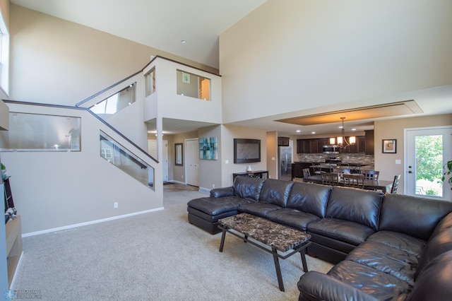 carpeted living room with a towering ceiling and a chandelier