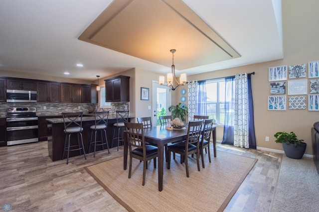 dining space with a notable chandelier and light hardwood / wood-style flooring