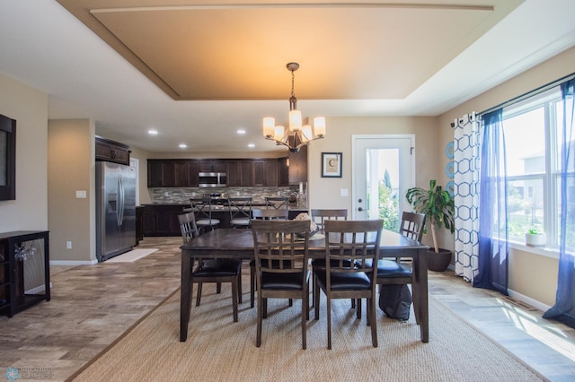 dining room with an inviting chandelier, light wood-type flooring, and a tray ceiling