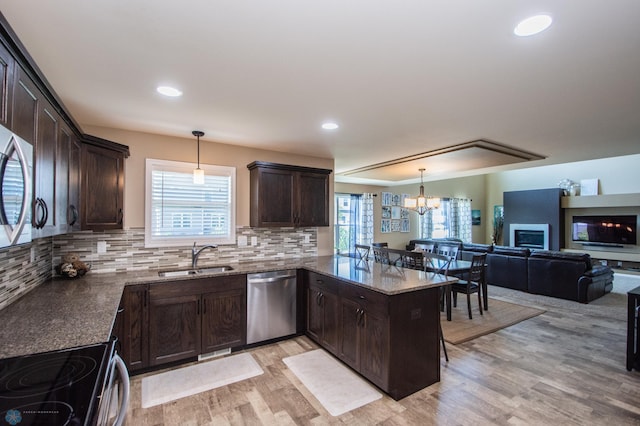 kitchen featuring tasteful backsplash, light wood-type flooring, kitchen peninsula, stainless steel dishwasher, and sink