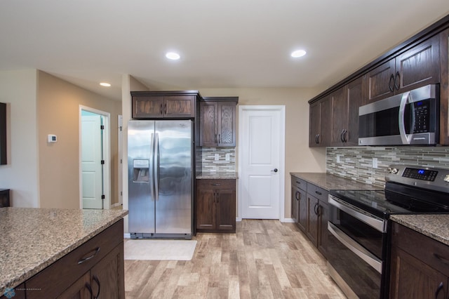 kitchen with stainless steel appliances, light hardwood / wood-style floors, dark brown cabinetry, decorative backsplash, and light stone countertops