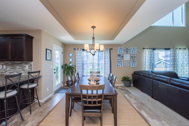 dining room featuring a chandelier, a tray ceiling, and light hardwood / wood-style floors