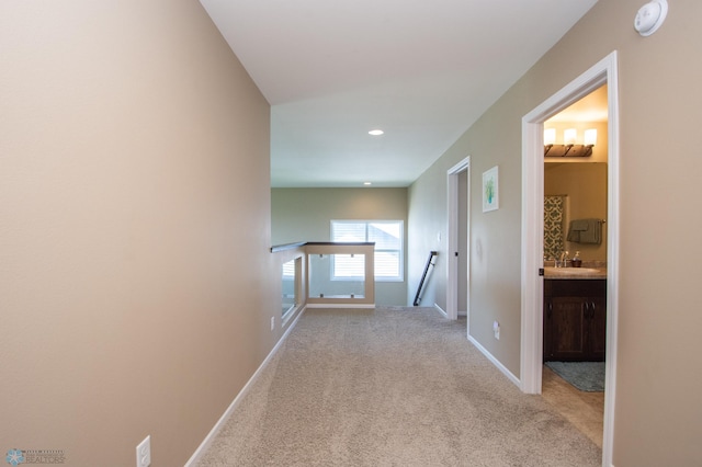 hallway with sink and light carpet