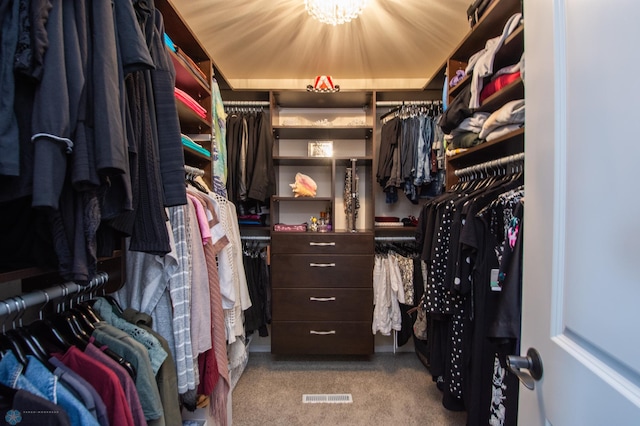 spacious closet with light colored carpet and a tray ceiling