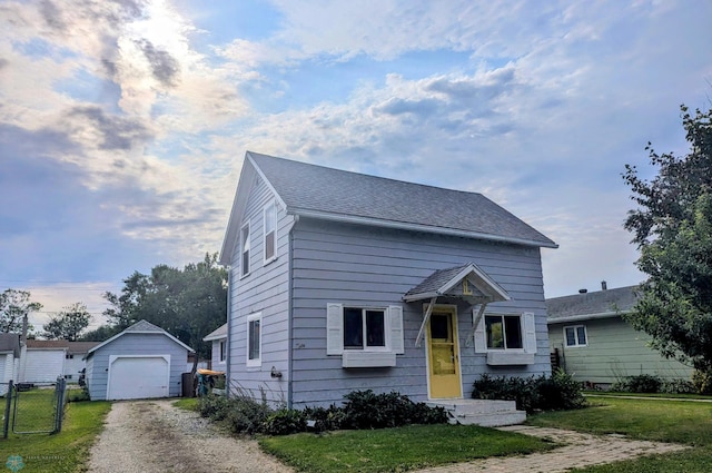 view of front of house with a front yard, a garage, and an outdoor structure