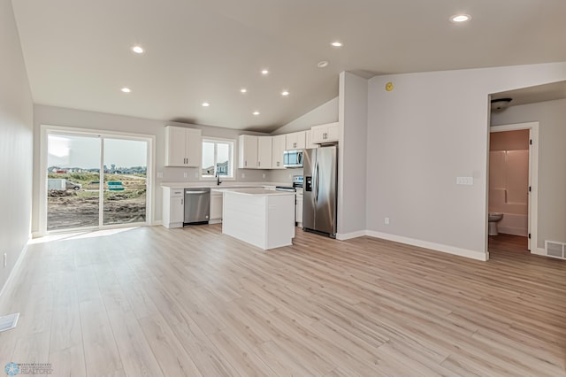 kitchen featuring stainless steel appliances, white cabinets, high vaulted ceiling, a center island, and light hardwood / wood-style floors