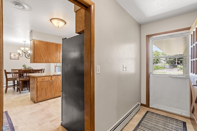 interior space featuring light tile patterned floors, an inviting chandelier, kitchen peninsula, baseboard heating, and black fridge