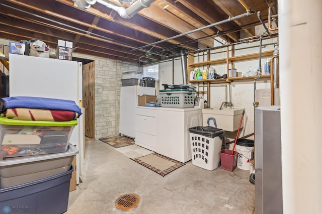 basement with white fridge, washer and dryer, and sink