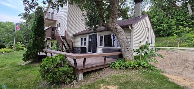 rear view of house featuring a deck, a balcony, and a yard