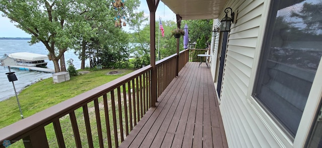 wooden deck with a water view and a lawn