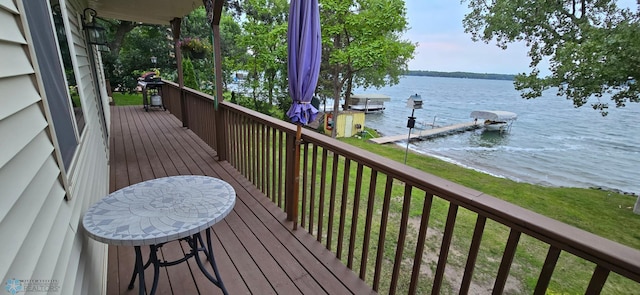 deck with a boat dock, a water view, and a yard