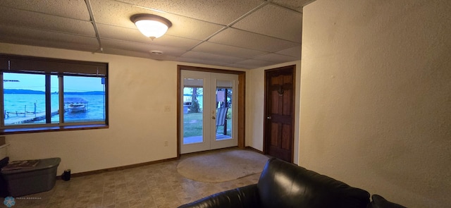 tiled foyer featuring a drop ceiling, a water view, and french doors